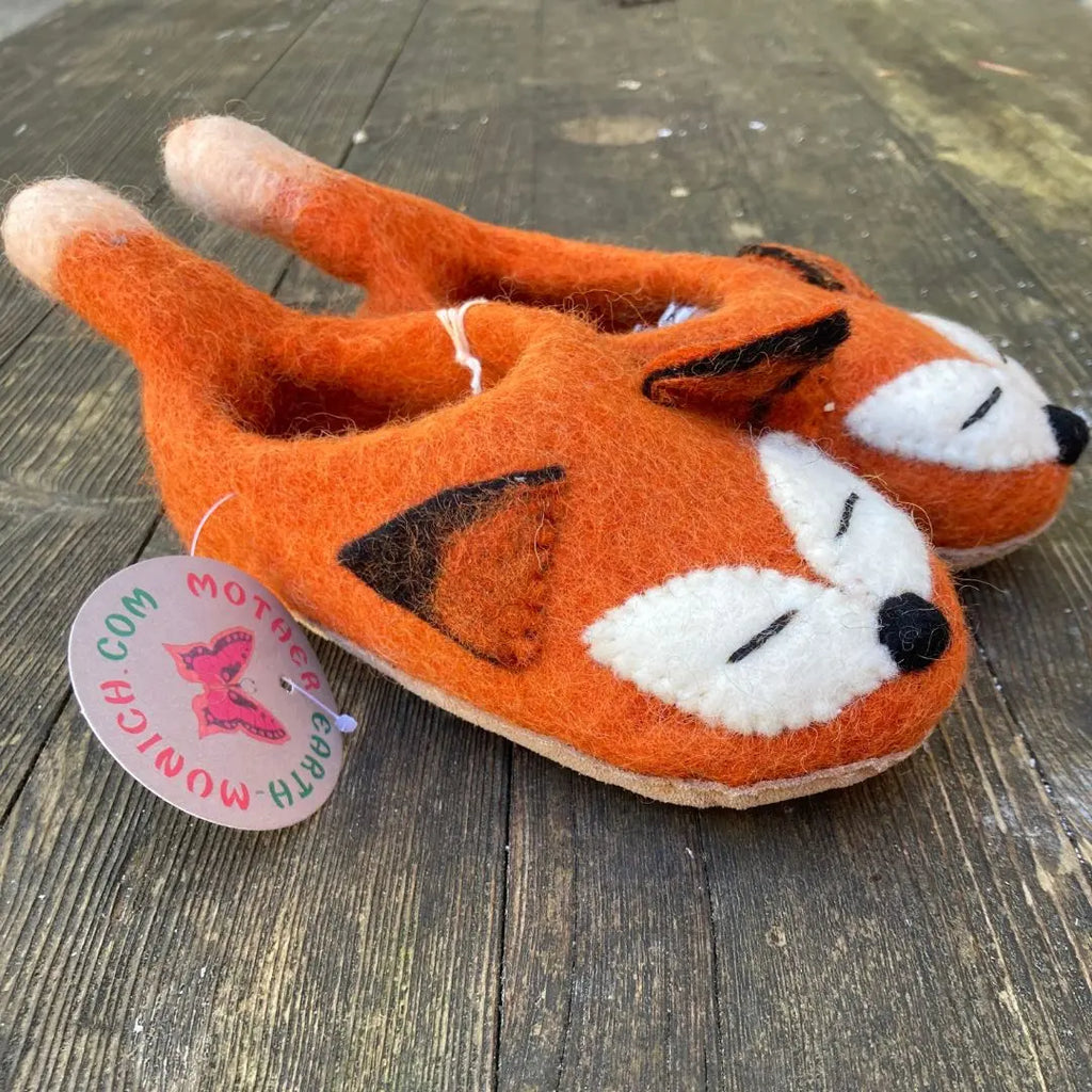 Fuchs - handgemachte Filzpantoffeln für Erwachsene in Orange mit Fuchsdesign auf holzigem Hintergrund.