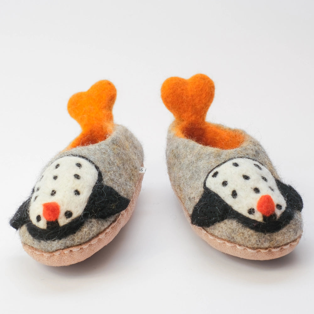 Pinguin Filzpantoffeln Halbschuh Kinder,  mit herzförmigen Schwalbenschwanz Watscheln, gelb orange und außen grauer Untergrund, innen orange gelb, Körper des Pinguin Motivs weiß mit schwarzen Punkten, schwarze Flügel, orangener Schnabel. Der Pinguin schaut hoch zum Kind. Hochgezogene Wildedersohle Marke: MAUSSCHUH by MotherEarth-Munich Ansicht: Von Vorne 