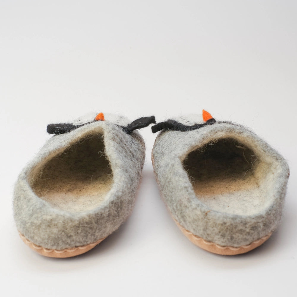 Pinguin Filzpantoffeln Halbschuh Erwachsene, silbergrauer Untergrund, innen naturweiß, Körper des Pinguin Motivs weiß mit schwarzen Punkten, schwarze Flügel, orangener Schnabel. Der Pinguin schaut nach außen zum Kind. Hochgezogene rutschfeste Wildedersohle Marke: MAUSSCHUH by MotherEarth-Munich Ansicht: Von Hinten